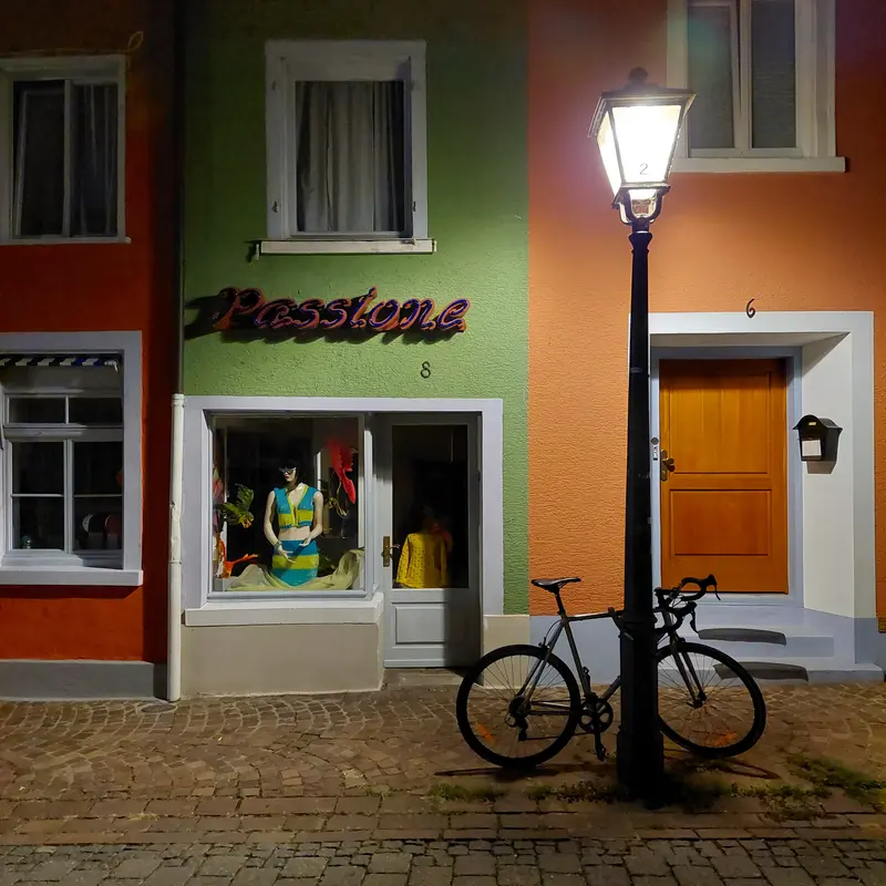 A bicycle against a streetlamp by night with colorfull walls behind